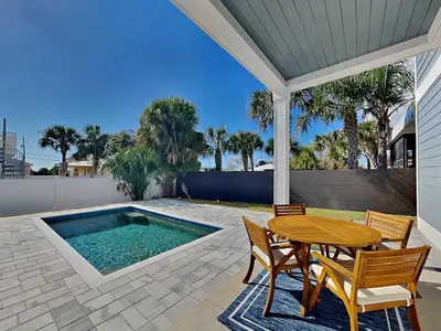 a patio with a table and chairs and a swimming pool at Horizon Dreams in Panama City Beach
