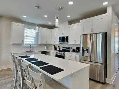 a kitchen with white cabinets and a stainless steel refrigerator at Horizon Dreams in Panama City Beach