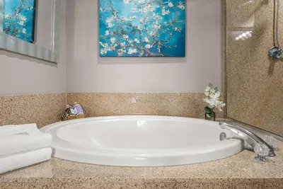 a bath tub in a bathroom with a painting at Luxe Glam 3BD Retreat! Gulf View Family Resort! in Panama City Beach