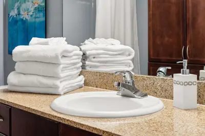 a bathroom counter with a white sink and towels at Luxe Glam 3BD Retreat! Gulf View Family Resort! in Panama City Beach