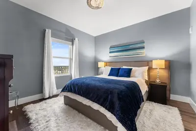 a bedroom with a bed with a blue blanket and a window at Luxe Glam 3BD Retreat! Gulf View Family Resort! in Panama City Beach