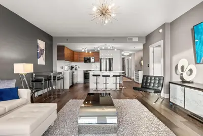a living room with a white couch and a kitchen at Luxe Glam 3BD Retreat! Gulf View Family Resort! in Panama City Beach