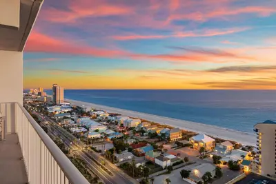a view of the beach at sunset from the balcony of a resort at Luxe Glam 3BD Retreat! Gulf View Family Resort! in Panama City Beach