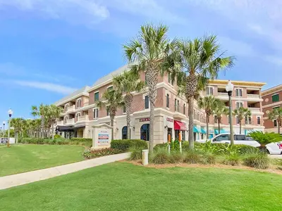 a large building with palm trees in front of it at Absolutely Paradise II l Heated 5000 sqft resort style pool l Walk to many restaurants in Santa Rosa Beach