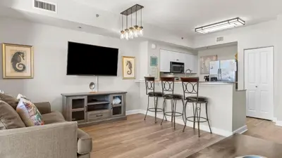 a living room with a couch and a bar with stools at Beachfront Condo Oceanview Balcony Lagoon Pool Thomas Dr 2308 by AvantStay in Panama City Beach