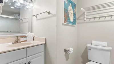 a white bathroom with a sink and a toilet at Beachfront Condo Oceanview Balcony Lagoon Pool Thomas Dr 2308 by AvantStay in Panama City Beach