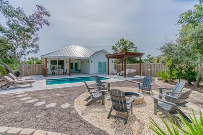 a backyard with chairs and a swimming pool at Bid A Wee Bungalow l Outdoor living l Private Pool & Private Beach Access l EV Charging in Panama City Beach