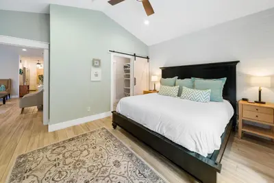 a bedroom with a large bed and a living room at Bid A Wee Bungalow l Outdoor living l Private Pool & Private Beach Access l EV Charging in Panama City Beach