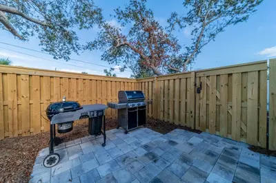 a backyard with a barbecue grill and a fence at Bid A Wee Bungalow l Outdoor living l Private Pool & Private Beach Access l EV Charging in Panama City Beach