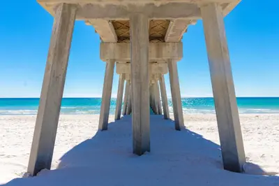 a wooden pier on a beach with the ocean at Bid A Wee Bungalow l Outdoor living l Private Pool & Private Beach Access l EV Charging in Panama City Beach