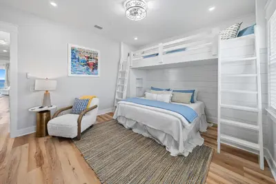 a bedroom with a bunk bed and a chair at Blessings at Pier Park l Luxury l Gulf Front Oasis with Private Pool l Steps From Pier Park in Panama City Beach