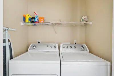 a laundry room with two white washers and a shelf at Blue Palm l Minutes to Sandy White Beach l Bike to Rosemary Beach in Inlet Beach