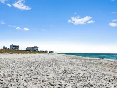 a sandy beach with buildings in the distance and the ocean at Blue Palm l Minutes to Sandy White Beach l Bike to Rosemary Beach in Inlet Beach