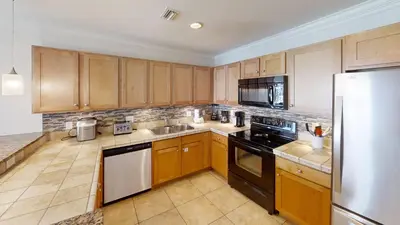 a kitchen with wooden cabinets and black appliances at Origins at Seahaven 1504 in Panama City Beach