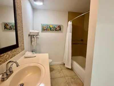 a bathroom with a sink and a tub and a toilet at Origins at Seahaven 1504 in Panama City Beach