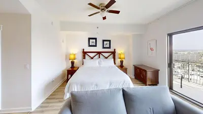 a bedroom with a bed and a couch and a window at Origins at Seahaven 1429 in Panama City Beach
