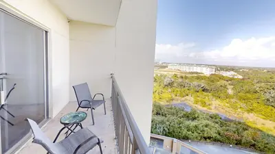 a balcony with two chairs and a large window at Origins at Seahaven 819 in Panama City Beach