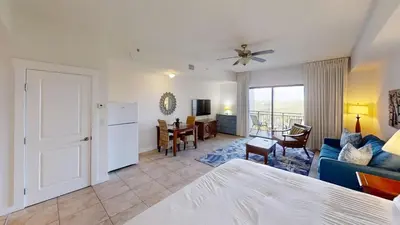 a room with a bed and a kitchen and a living room at Origins at Seahaven 819 in Panama City Beach