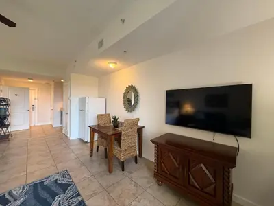a living room with a large flat screen tv on a wall at Origins at Seahaven 819 in Panama City Beach