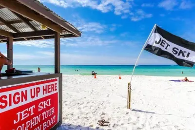 a sign on a beach with a flag on it at Origins at Seahaven 819 in Panama City Beach