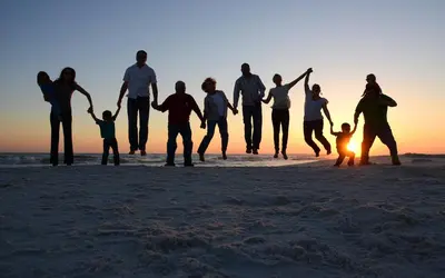 a group of people walking on the beach at sunset at Origins at Seahaven 819 in Panama City Beach