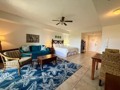 a living room with a blue couch and a bed at Origins at Seahaven 819 in Panama City Beach