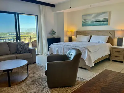 a bedroom with a bed and a couch and a table at Origins at Seahaven 709 in Panama City Beach