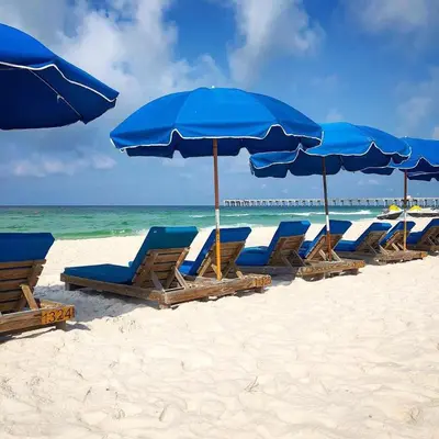 a row of blue chairs and umbrellas on a beach at Origins at Seahaven 709 in Panama City Beach