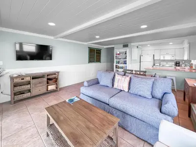 a living room with a blue couch and a table at Commodores 101 l Beachfront l Corner Unit with Pristine Beach Views l Community Pool in Santa Rosa Beach
