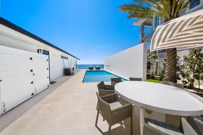 an outdoor patio with a white table and chairs and the ocean at Dream On l Beachfront l Golf cart and 4 Bikes Included l Gulf Front Private Pool in Seacrest