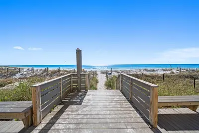 a wooden walkway to the beach with two benches at Eastern Shores 101 l Beachfront l Ground level with direct access to beach and pristine views in Santa Rosa Beach