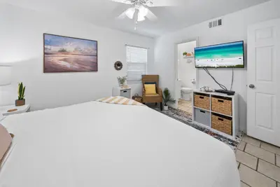 a bedroom with a large white bed and a flat screen tv at Eastern Shores 101 l Beachfront l Ground level with direct access to beach and pristine views in Santa Rosa Beach