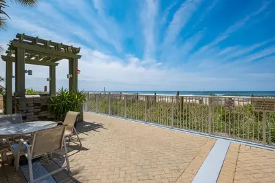 a patio with a table and chairs and the beach at Emerald Isle l Beachfront l Amazing beach views l Heated Community Pool l Fitness center in Panama City Beach