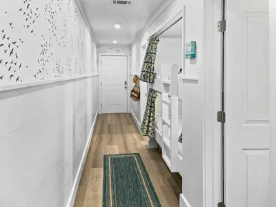 a hallway with white walls and a door with a green rug at Endless Waves 208 l Beachfront l Stunning Beach Views l Bike to Seaside in Santa Rosa Beach