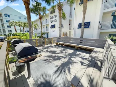 a picnic bench in front of a building with palm trees at Endless Waves 208 l Beachfront l Stunning Beach Views l Bike to Seaside in Santa Rosa Beach