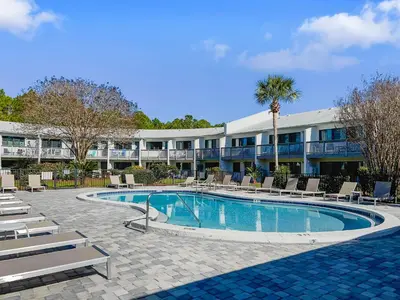 a hotel with a swimming pool and chairs and a building at Hidden Beach Villas 111 l Heated community pool l Tennis and Shuffleboard l Across from the Beach in Santa Rosa Beach