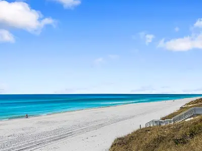 a beach with people walking on the sand and the ocean at Hidden Beach Villas 111 l Heated community pool l Tennis and Shuffleboard l Across from the Beach in Santa Rosa Beach
