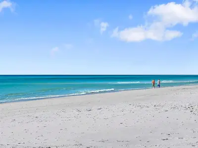 two people standing on a beach near the ocean at Hidden Beach Villas 111 l Heated community pool l Tennis and Shuffleboard l Across from the Beach in Santa Rosa Beach