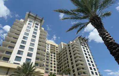 a tall building with a palm tree in front of it at Origin at Seahaven 423 in Panama City Beach