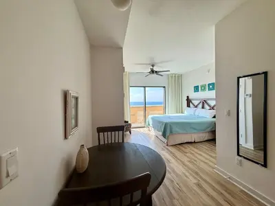 a bedroom with a bed and a table and a window at Origin at Seahaven 402 in Panama City Beach