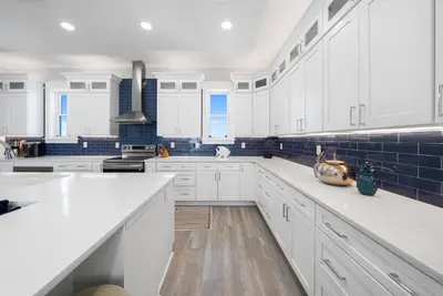 a white kitchen with white cabinets and blue tiles at Joy by the Sea l Private heatable pool l Beach Front l Family Activities nearby in Panama City Beach