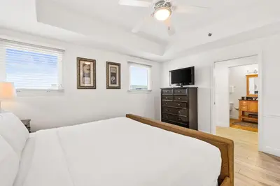 a white bedroom with a bed and a tv at Sterling Breeze 307 by Emerald Coast Retreats in Panama City Beach