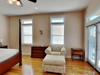 a bedroom with a bed and a chair and windows at The Mermaid in Rosemary Beach
