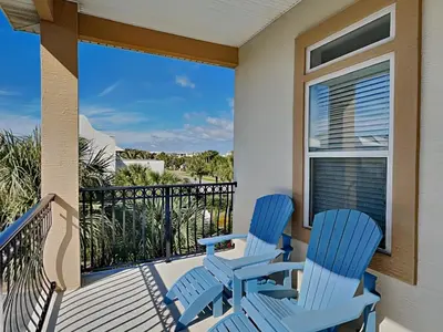 two blue chairs on a balcony with a view of the ocean at The Mermaid in Rosemary Beach