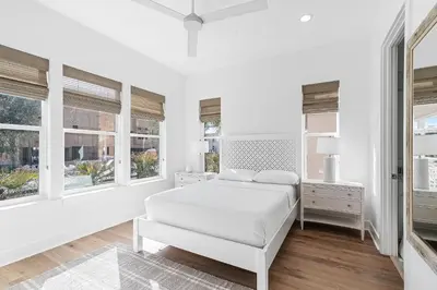 a white bedroom with a bed and windows at Pompano In Paradise in Inlet Beach