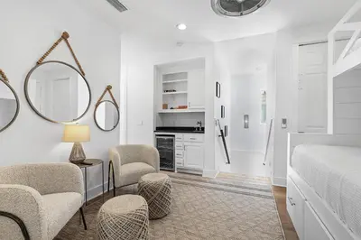 a bedroom with a bed and two chairs and a mirror at Pompano In Paradise in Inlet Beach