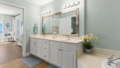 a bathroom with two sinks and a large mirror at Gulf-Front PCB Condo w Balcony Resort Amenities Game Room Pools Beach Gear Tortuga 1301 by AvantStay in Panama City Beach