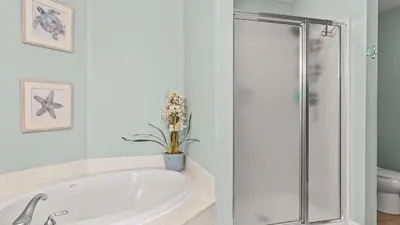 a white bathroom with a tub and a shower at Gulf-Front PCB Condo w Balcony Resort Amenities Game Room Pools Beach Gear Tortuga 1301 by AvantStay in Panama City Beach