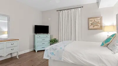 a bedroom with a bed and a dresser with a television at Gulf-Front PCB Condo w Balcony Resort Amenities Game Room Pools Beach Gear Tortuga 1301 by AvantStay in Panama City Beach
