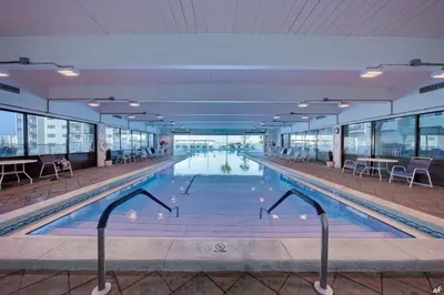 a swimming pool in a building with tables and chairs at Sunshine at PP A-914 in Panama City Beach